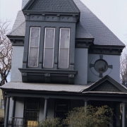 View of 2525 Champa Street in the Five Points neighborhood of Denver, Colorado. The residence is listed on the National Register of Historic Places as a contributing resource to the Curtis Park-Champa Street Historic District. The two-story brick Queen Anne house (c. 1885) has a full porch with a pediment above the entry, a bay with a pediment, cornice and fishscale shingles. There is an oriel window on the second floor and an oculus above the porch pediment.