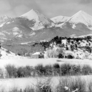 View of Howard (Fremont County), Colorado; shows the Stout School (District 13), later the Howard Volunteer Fire Department, snow, and Twin Sisters Peaks.
