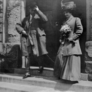 Charles and Hazel Gates pose on steps of Plymouth Congregational Church in Denver, Colorado after their wedding. Her outfit includes a straw hat and a bouquet of flowers.