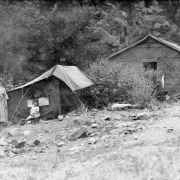 Sade and Mary Elizabeth Rhoads pose outside of a tent in Colorado. A tar papered shack is nearby.