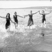 Women laugh and splash in a lake.