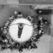 A man falls into a round Browder safety net at a fire department demonstration in Denver, Colorado. Men and Boy Scouts look on.