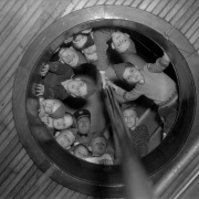 Boy Scouts of America troop members and their troop leader look down a fire pole hole in a Denver, Colorado firehouse.
