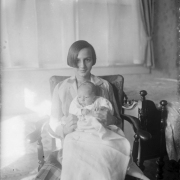 A woman in an armchair holds a baby.