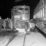 View of a car / streetcar crash; people look on, and signs read: "Knights Templar Easter Service," "40," and "803."