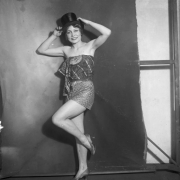 A young woman poses in a costume that includes shorts, high heels, print fabric, and a stovepipe hat.