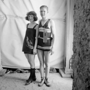 A teenaged boy and girl pose in their swimming suits. Her costume has an appliqued bird.