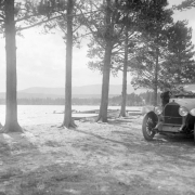 View of a convertible automobile by a lake, among trees, probably in Colorado.