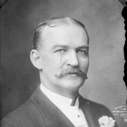 Portrait of an unidentified man with a moustache, tie, and boutonniere.