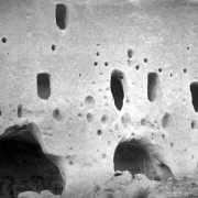 Close-up view of the Puye Cliffs, Native American (Tewa) tuff dwellings, at Puye Cliff Dwellings, Santa Clara Pueblo, New Mexico. The cliffs have arched doorways that stand underneath holes for vigas.