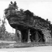 A view of the old bear and sea lion habitat at the Denver Zoo in City Park in Denver, Colorado. Trees and foliage cover the rocks and boulders. The steel and plaster structure was completed in 1918 at the size of 185 feet long and 45 feet high.
