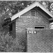 View of a brick restroom building at Sloan's Lake Park in Denver, Colorado. A sign painted on a brick dividing wall reads: "Men".