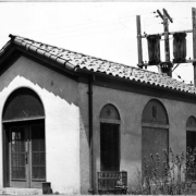 View of an adobe style water pump house at Berkeley Park in Denver, Colorado. The building has a tile roof.