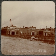 View of the Denver Engineering Works Company buildings on 30th (Thirtieth) and Blake Streets in Denver, Colorado. A bicycle lies near the dirt street. The brick buildings read: "Erec[t]ing And Boiler Shop", "Exc[e]lsior Steam Engine Works", and "Pattern Shop".