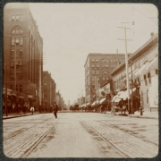 View of possibly 17th (Seventeenth) Street in Denver, Colorado. Men walk across the street and horse-drawn buggies are parked along the side. A sign reads: "Dental [?]".