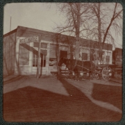 A horse-drawn wagon is parked near a butcher shop in Denver, Colorado. A sign reads: "Meat Market".