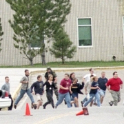 Students sprint across a parking lot toward school buses waiting to evacuate them.