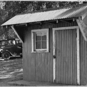 View of the gas station and pump at the Wellshire Golf Course (Wellshire Country Club) in Denver, Colorado. Automobiles are parked nearby. A sign near the pump reads: "Conoco Germ Processed Parafin Base Motor Oils".