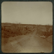 View of a dirt road, small bridge, and farm building possibly near Denver, Colorado.