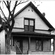 View of a house near Elyria Park in Denver, Colorado. The two-story brick house has a covered porch.