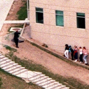 Terrified students edge nervously up a hill against a wall of the school while police search for the gunmen.