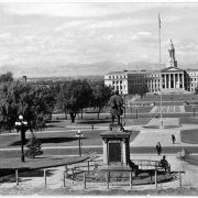 A view of Civic Center Park in Denver, Colorado from the State Capitol Building. Shows the Civil War Memorial from behind, the City and County Building, landscaping, and a canon.