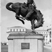 View of a statue of a cowboy on a bucking bronco in Civic Center Park in Denver, Colorado. The statue was sculpted by Denver artist Alexander Phimister Proctor. A plaque on the statue reads: "'Broncho Buster' presented to Denver by J.K. Mullen A.D. 1920."