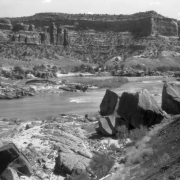 Sandstone cliffs of Ruby Canyon, in Utah or Colorado, edge the Colorado River. Pinnacles comprise the "Three Sisters" formation.