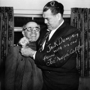 Jack Dempsey poses with Joe "Awful" Coffee probably in Colorado. Both men wear suits.