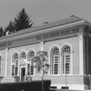 View of the Roger W. Woodbury (1841-1903) Branch Library  (1912; Jacques Benedict, architect) at 3265 Federal Boulevard in the West Highland neighborhood of Denver, Colorado. Shows an asymmetrical, one-story, Italian Renaissance-style building with brick walls and terracotta trim. The low pitch, hipped roof is covered with tiles. Other notable features include arched ribbon windows, pilasters and a pedimented main entrance with Corinthian columns.