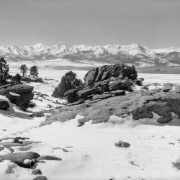 Rocks, trees, and wide fields edge De Weese Reservoir in Custer County, Colorado; the Sangre De Cristo Range is in the distance.
