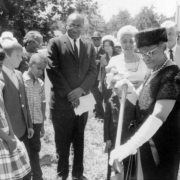 Lillian Bondurant uses a shovel at the ground breaking ceremony of the George Washington Carver Day Nursery at 2260 Humboldt Street in the City Park West neighborhood of Denver, Colorado. Reverend M. C. Williams, Dorothy Reeves, and a group of children stand nearby.