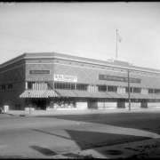 Exterior view of the Broadway Department Store Co. at South Broadway and Archer Place in Denver, Colorado; sign reads:  "Hi Mr. Tourist! Ask Questions Here"; washtubs in window display.