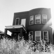 View of a two-story brick house at 2550 Arapahoe Street in the Five Points (Curtis Park) neighborhood of Denver, Colorado. The building has a covered entryway and arched front wall with windows.