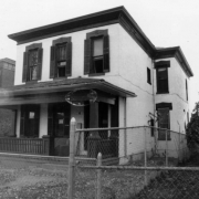 View of a house at 2915 Champa Street in the Five Points (Curtis Park) neighborhood of Denver, Colorado. The two-story brick house has a covered porch, decorative shutters, and window trim.