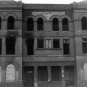 View of an abandoned apartment building at 816 25th Street in the Five Points neighborhood of Denver, Colorado. The three-story building has boarded up arched windows and decorative brick work.