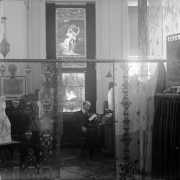 Interior view of Daniels and Fisher administrative offices, in Denver, Colorado; shows a man at a roll top desk. Decor includes stained glass windows, lace, chintz, a tapestry, a hanging lamp, and a statue of Venus.