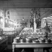 Interior view of the Daniels and Fisher store in Denver, Colorado; shows displays of China dinnerware, cut crystal glass, a lamp, United States and International flags.