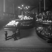 Interior view of the Daniels and Fisher store in Denver, Colorado; shows glass display cases, some with porcelain figurines, a wood parquet floor, and a sign: "Easter Novelties."
