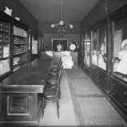Interior view of the Daniels and Fisher store in Denver, Colorado; shows a counter, chairs, children's shoes, and glass cases with infants apparel and dolls.