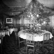 Interior view of a Daniels and Fisher Store showroom, in Denver, Colorado; shows tables set with silver, dinnerware, and arrangements of roses. Garlands hang from lamps.