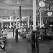 Interior view of the Daniels and Fisher store, in Denver, Colorado; shows glass display cases, lamps, and a mezzanine.