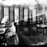 Interior view of the Daniels and Fisher Stores Company, in Denver, Colorado; shows women at tables with mirrors, cosmetics, flowers, and an ash tray.
