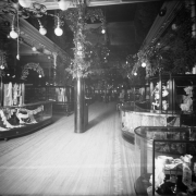 Interior view of the Daniels and Fisher store in Denver, Colorado; shows glass display cases of lace, and arrangements of pine boughs.