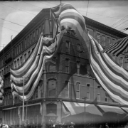 View of the Daniels and Fisher store, at 16th (Sixteenth) and Curtis Streets in Denver, Colorado; shows a United States flag and a large banner.