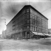 Exterior view of the Daniels and Fisher store in Denver, Colorado; shows storefronts, and horses and buggies.