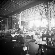 Interior view of the Daniels and Fisher store in Denver, Colorado; shows crystal, china, lamps, pottery, buffets, palms, a wooden screen, and International flags. Sign reads: "Oriental Rugs."