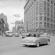 View of 17th (Seventeenth) Street in Denver, Colorado; shows automobile and bus traffic, and the Brown Palace Hotel.
