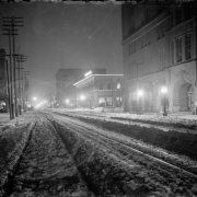 Night view of 17th (Seventeenth) Street in Denver, Colorado, at night; shows the Brown Palace Hotel, the Gas and Electric Building, and snow.