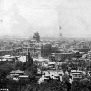 Rooftop view of downtown Denver, Colorado. Buildings include the Arapahoe County Courthouse. Signs read: "The Shannon Reid Plumbing and Heating Co" and "Uhland's Drug Store."